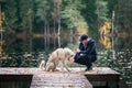 Man with a husky dog Ã¢â¬â¹Ã¢â¬â¹on the pier of a beautiful lake, autumn mood. Young man training a dog in nature